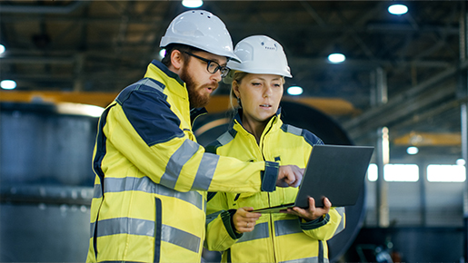 Man and woman with hardhats looking at laptop